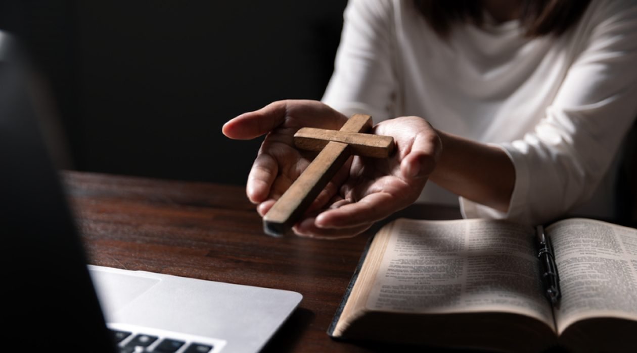 Christian online technology concept. Hands praying of christian with digital computer laptop, Online live church for sunday service. Asian catholic man are reading Holy bible book and online study.