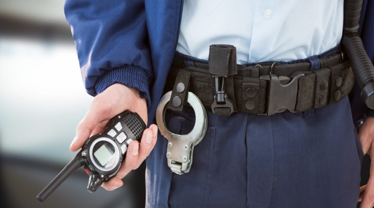 Composition of midsection of male security guard holding walkie talkie over blurred background. security and safety concept digitally generated image.