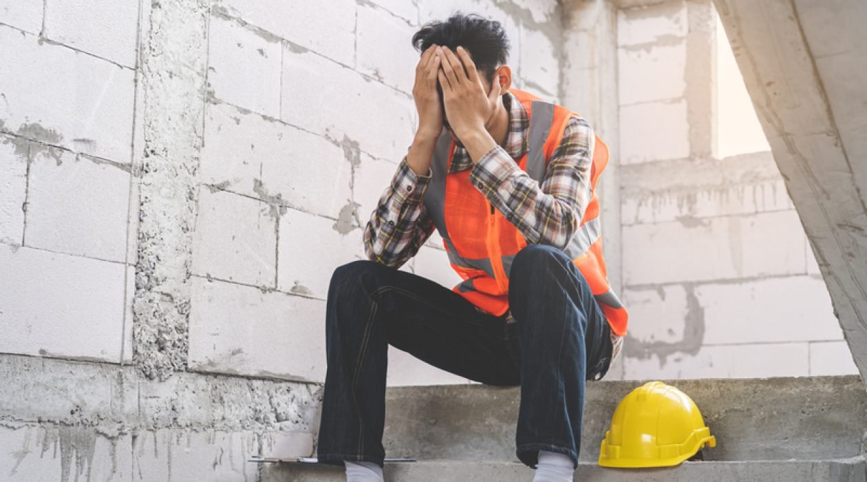 Engineer industry unemployed. Feeling stress, tired and headache asian man sitting depressed on stair at site, worker male crisis in factory, fired unemployment from economy, lost job, jobless concept